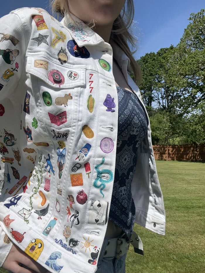 Close-up of a white jacket featuring detailed Gen-Z pop culture patches worn by a woman