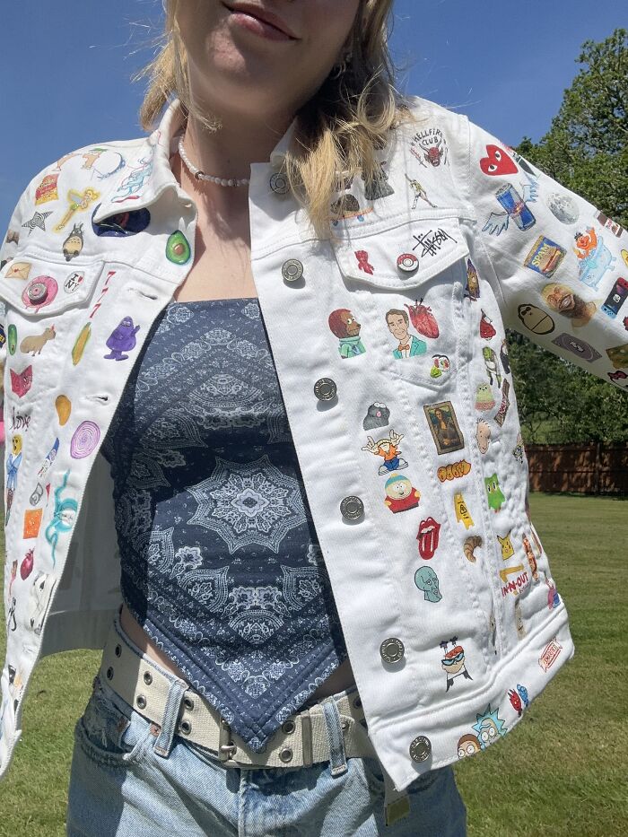 Woman wearing a decorated white jacket with various Gen-Z pop culture patches in sunlight