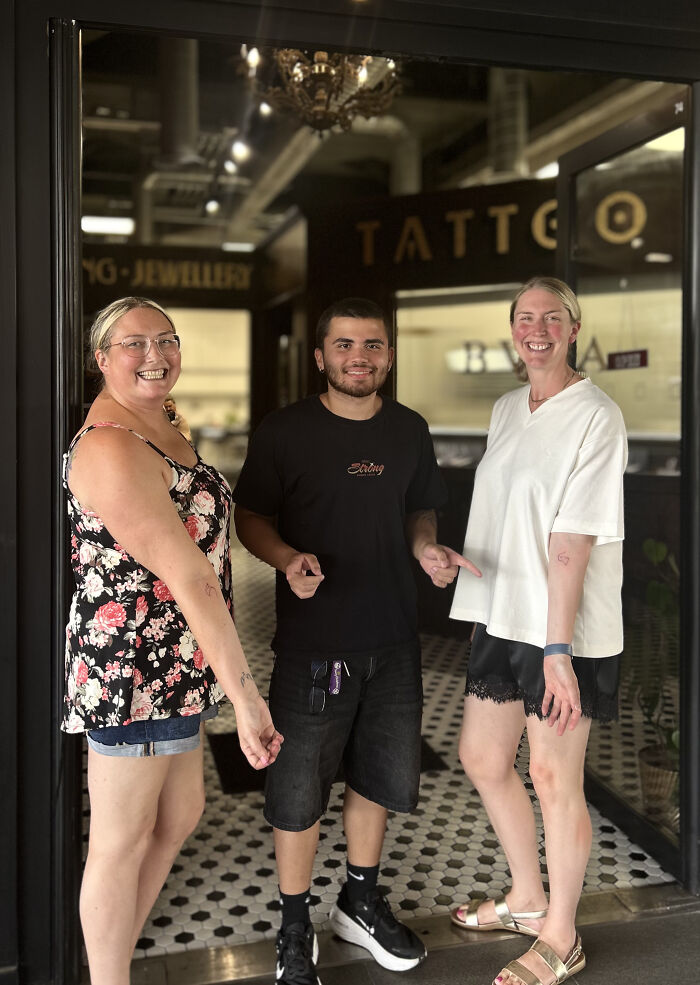 Matching ink ideas: two people with matching heart tattoos on their forearms, standing with a tattoo artist.