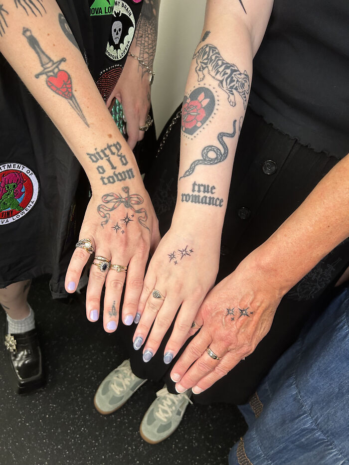 Close-up of three people's hands and forearms displaying various matching ink ideas, including small stars and text tattoos.
