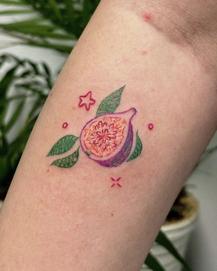 Vibrant crayon drawing-inspired tattoo of a fig with leaves and stars, showcasing childhood creativity.