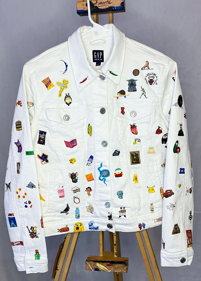 White denim jacket adorned with colorful Gen-Z pop culture patches displayed on an easel