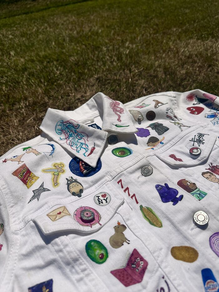 Close-up of the collar and upper front of a white denim jacket, intricately decorated with pop culture elements defining Gen-Z childhood.