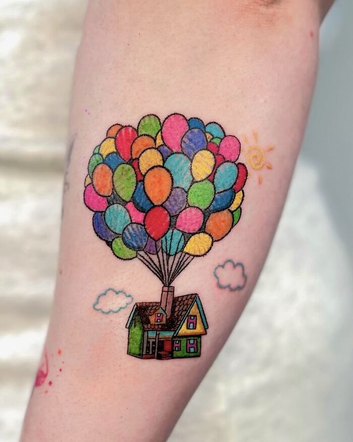 Up house with balloons crayon drawing inspired tattoo on a person's arm.
