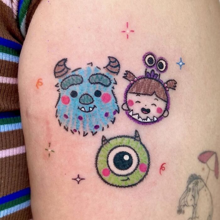 Colorful crayon drawing inspired tattoos of Monsters Inc characters on an arm.