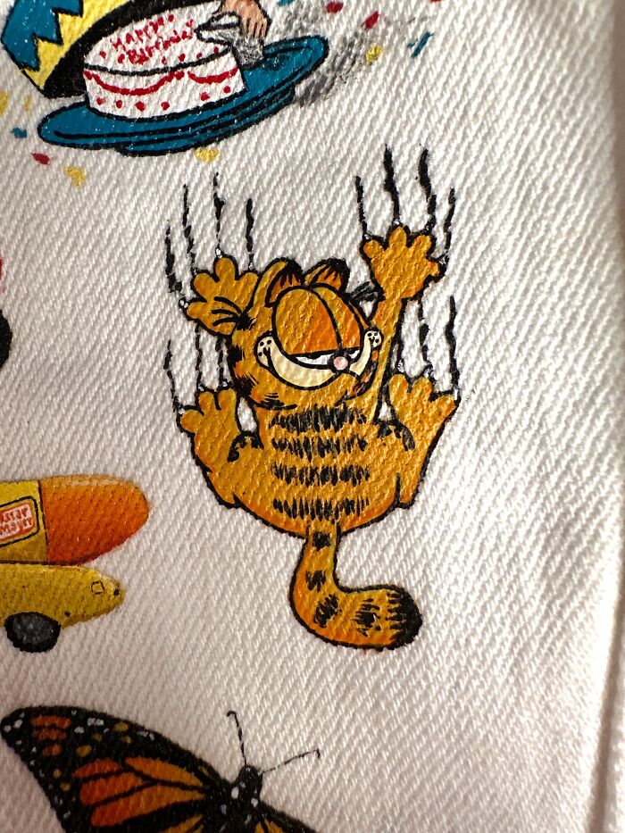 Hand-painted Garfield character scratching, part of a jacket filled with pop culture references from Gen-Z's childhood.