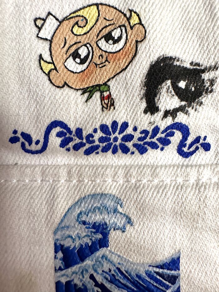 Artistic details on a pop culture jacket showing a character in cartoon style and a wave, celebrating Gen-Z childhood.