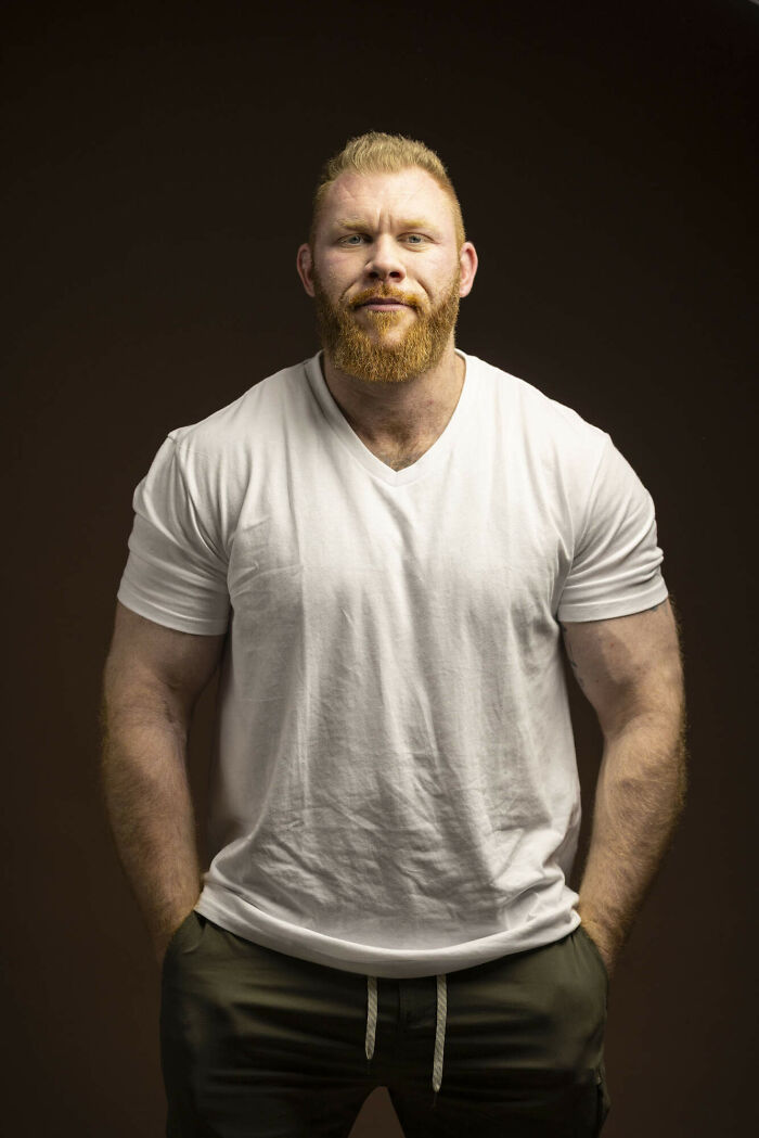 A man with natural redheads hair styled in an undercut, wearing a floral shirt, looking to the side.