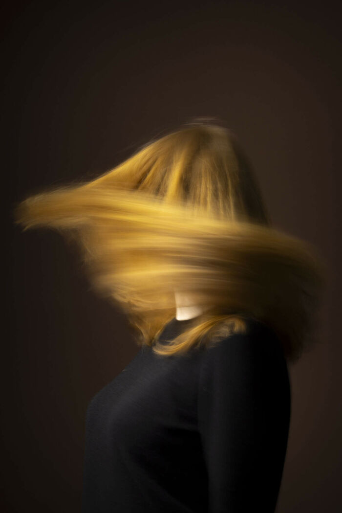 A beautiful natural redhead woman with long flowing hair covering her face, from a global portrait project.