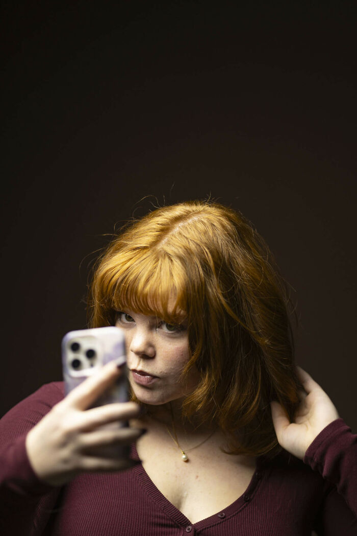 Portrait of a young natural redhead woman with long wavy hair, looking confidently for the portrait project.