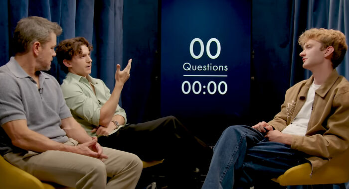 Matt Damon, Tom Holland, and another person in a discussion setting, with a screen displaying 'Questions' and '00:00'. Matt Damon, Tom Holland, and another person in a discussion setting, with a screen displaying 'Questions' and '00:00'.