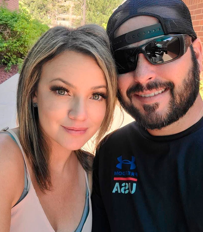 A Mom-Of-Four attacked by spiders, taking a selfie with a man wearing sunglasses and a cap.