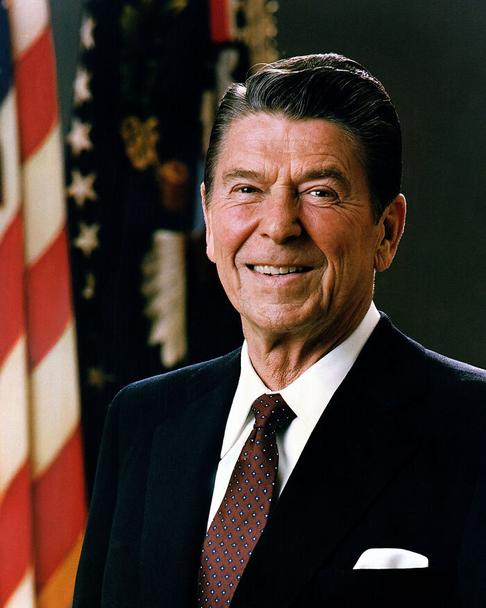 A portrait of Ronald Reagan smiling, standing in front of an American flag, related to political misconceptions.