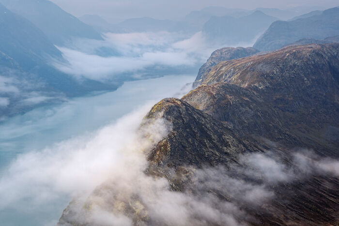 A breathtaking aerial view of misty mountains and a calm lake, captured at the International Nature Photography Festival.