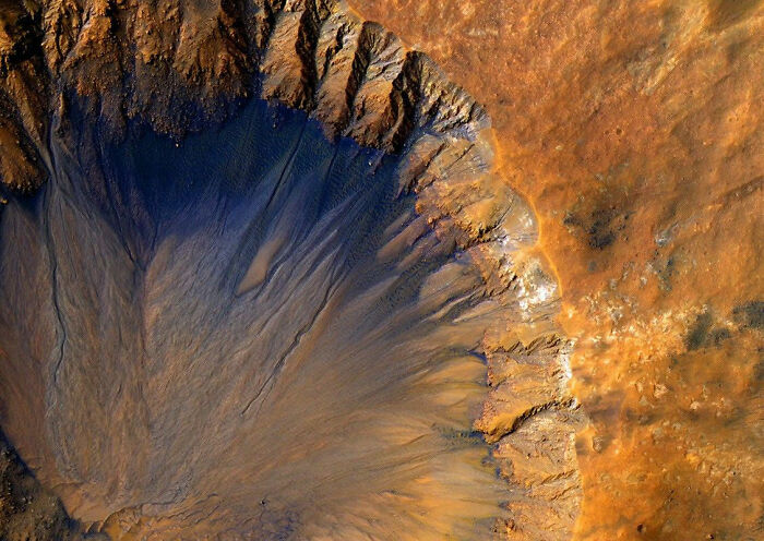 An aerial view of a Martian crater, its dark center fanning out like a jellyfish, captured in a NASA Mars photo. An aerial view of a Martian crater, its dark center fanning out like a jellyfish, captured in a NASA Mars photo.
