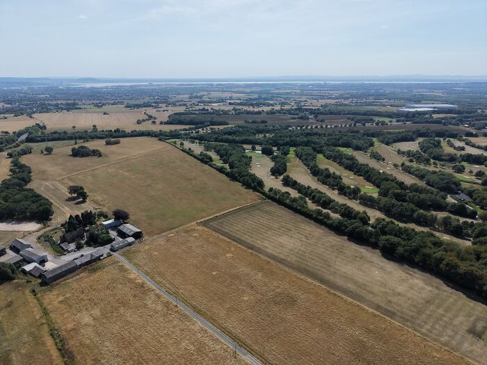 Vast aerial landscape showing dry fields and golf courses affected by Europe's brutal drought, raising questions about politics.
