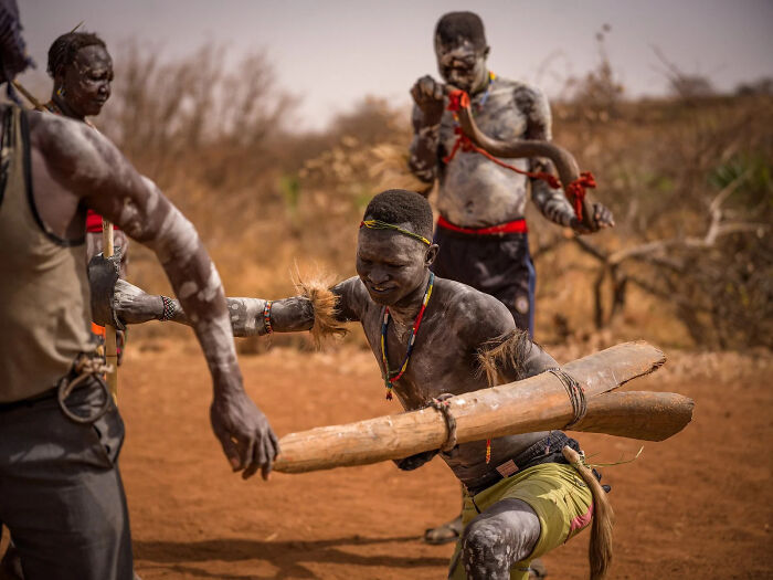 A group of men in traditional body paint engaged in a cultural practice in one of the European Photography Awards winning images.