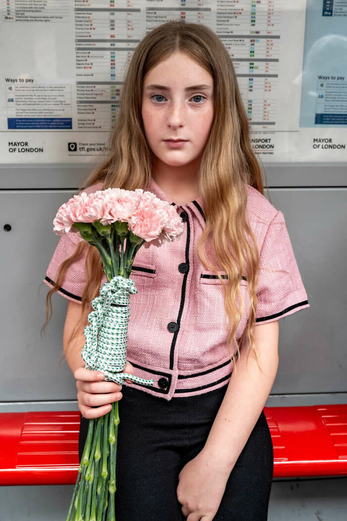 A young girl in a pink jacket holds a bouquet of flowers, a captivating moment from the LensCulture Street Photography Awards.