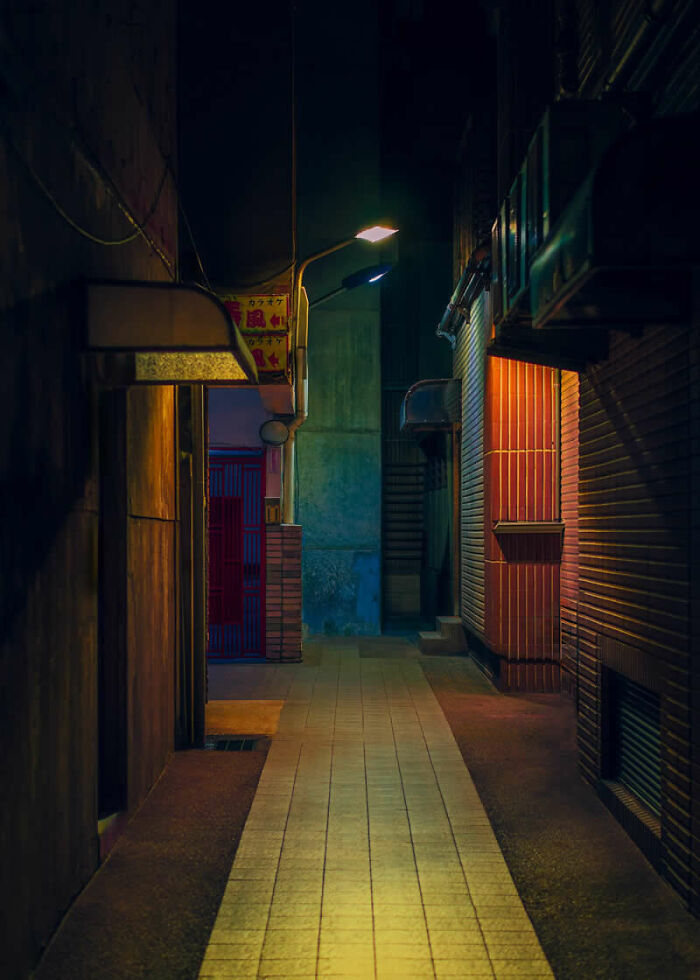 A narrow, dimly lit alleyway with a single light, an atmospheric scene from the LensCulture Street Photography Awards.