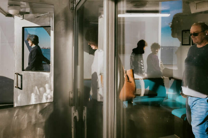 Reflective street photography with people on a ferry, captured for the LensCulture Street Photography Awards.