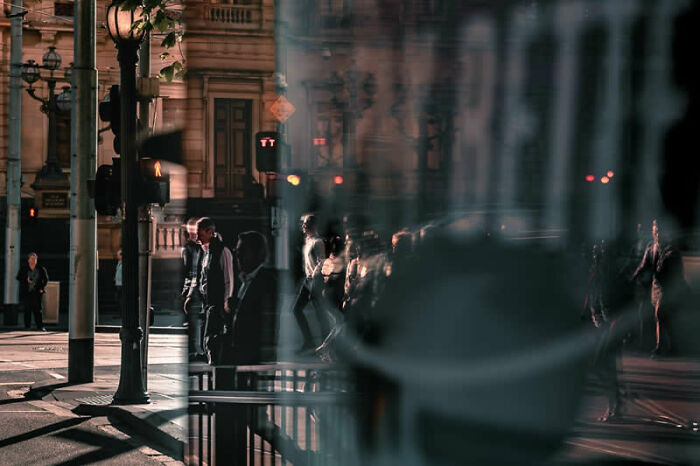 Blury street scene at night with city lights and pedestrians, capturing a moment for the Street Photography Awards.