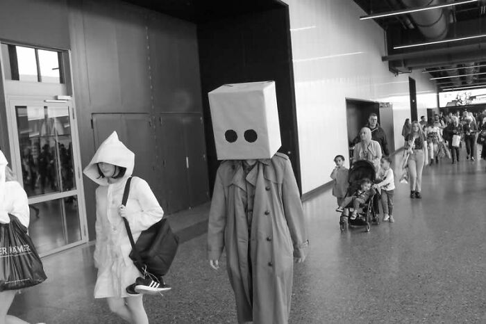 Two figures in unique costumes walk through a public space, a mesmerizing winning photo from the LensCulture Street Photography Awards.