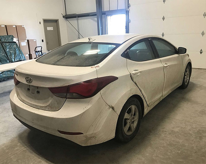 A dirty white sedan with rear damage parked indoors, possibly evidence. Questionable details in Bryan Kohberger's case.