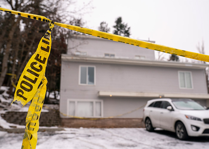 Police line tape in front of a house in the snow, related to questionable details in Bryan Kohberger's case.
