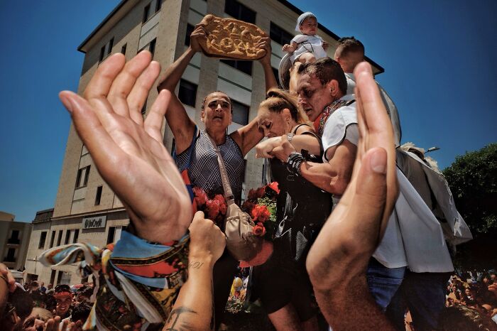 Crowd of people carrying objects and a baby, capturing life's authentic street photography moments.