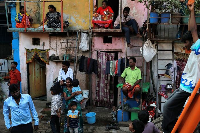 A vibrant street scene capturing authentic life, with people gathered in an alleyway of colorful, modest homes, a pure street photography award winner.