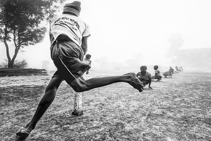 A man mid-leap in a rural setting, capturing a dynamic authentic moment of street photography.