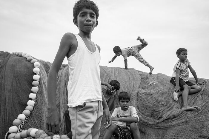 A group of children engaging in playful activities on fishing nets, showcasing authentic moments of street photography.