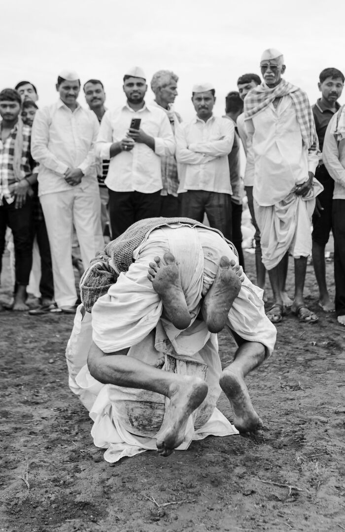 Two individuals engaged in a traditional wrestling pose, capturing an authentic moment in street photography.