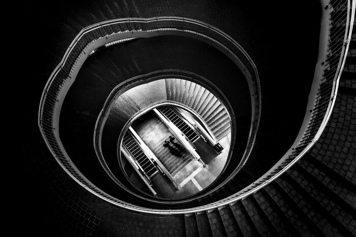 A high-angle black and white shot of a spiral staircase showing authentic street photography.