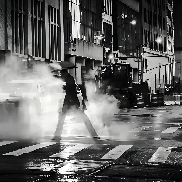 A person crossing a steamy street at night, embodying authentic street photography.