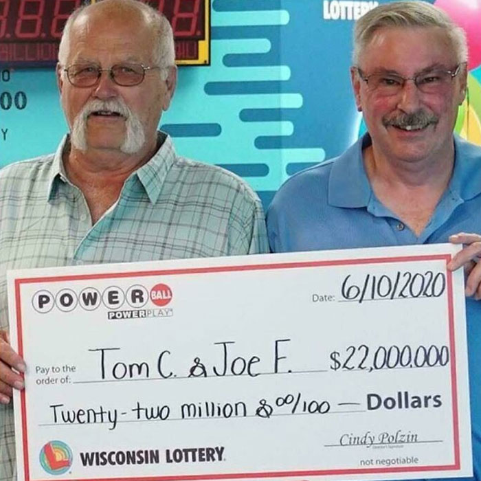 Two men smiling while holding a large check for $22,000,000.00 from the Wisconsin Lottery, showing how people got rich.