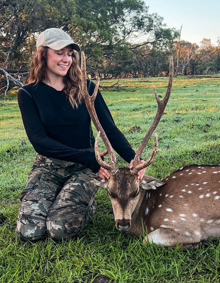 Smiling woman kneeling beside a spotted deer with antlers, linking to the US tourist's court fate for a snatched baby wombat. Smiling woman kneeling beside a spotted deer with antlers, linking to the US tourist's court fate for a snatched baby wombat.