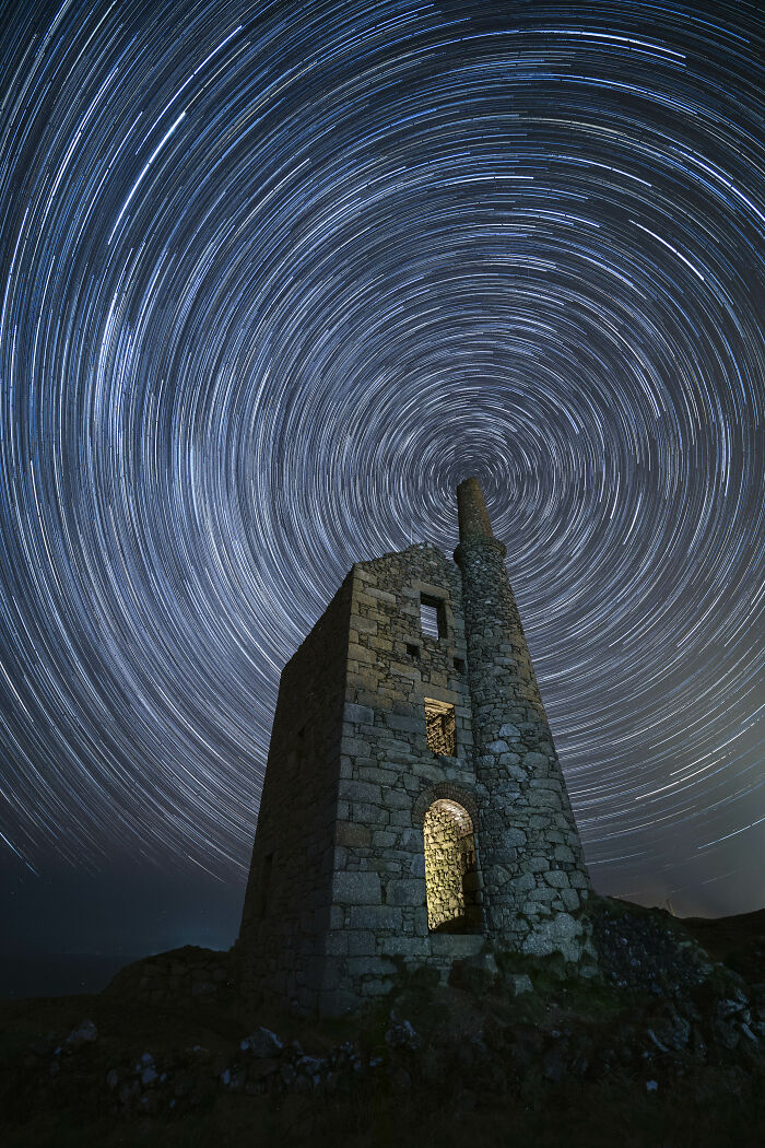 Star trails create concentric circles above an old stone building in an astronomy photo from the ZWO Shortlist.
