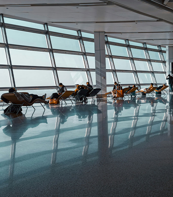 Travelers relax in an airport terminal with large windows, showcasing the modern airport environment. Travelers relax in an airport terminal with large windows, showcasing the modern airport environment.