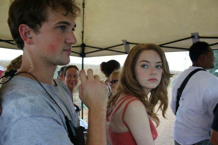 Emma Stone looks over her shoulder with a man nearby, possibly sharing what dating a celebrity is actually like.