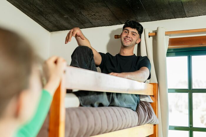 College life freedom: Young man relaxing on a bunk bed, representing the personal freedom of college life.
