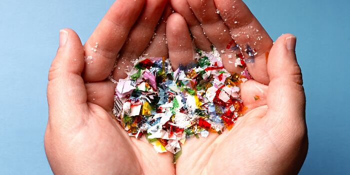 Hands holding colorful shredded plastic and glitter, depicting scary science facts related to microplastics and pollution.