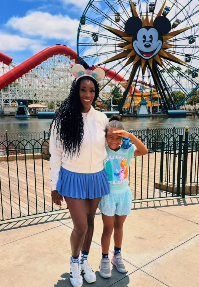 Mom and daughter enjoying their mornings at a theme park, with a large Ferris wheel behind them. Mom and daughter enjoying their mornings at a theme park, with a large Ferris wheel behind them.