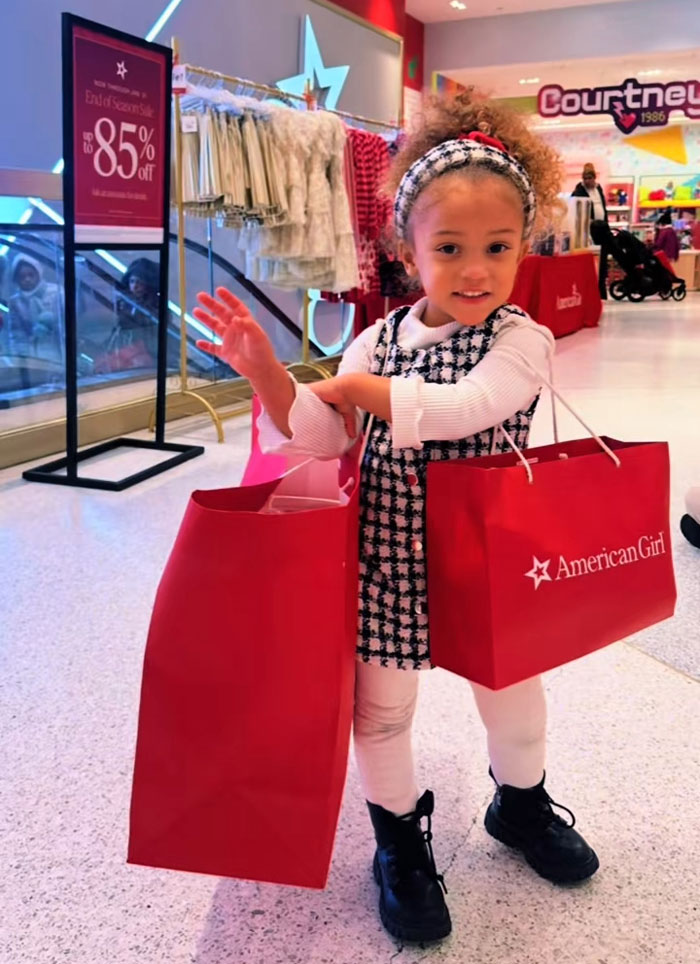 A young girl happily holding American Girl shopping bags, representing kids spending mornings reading and exercising. A young girl happily holding American Girl shopping bags, representing kids spending mornings reading and exercising.