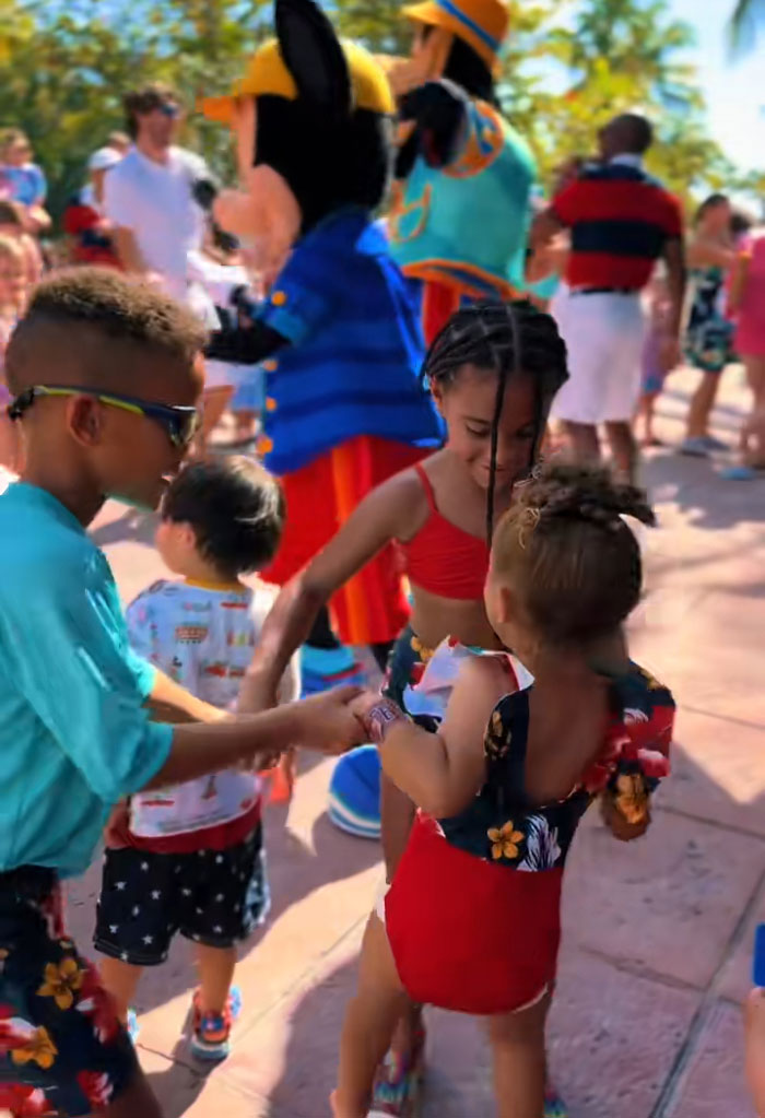 Kids holding hands at a party with a mascot, after their mornings of reading and exercising. Kids holding hands at a party with a mascot, after their mornings of reading and exercising.