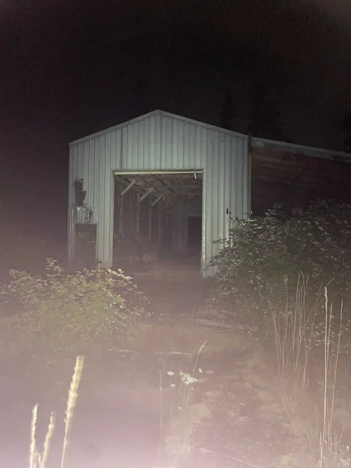 Nighttime view of an abandoned metal barn with an open door, a perfect subject for urban exploration with location.