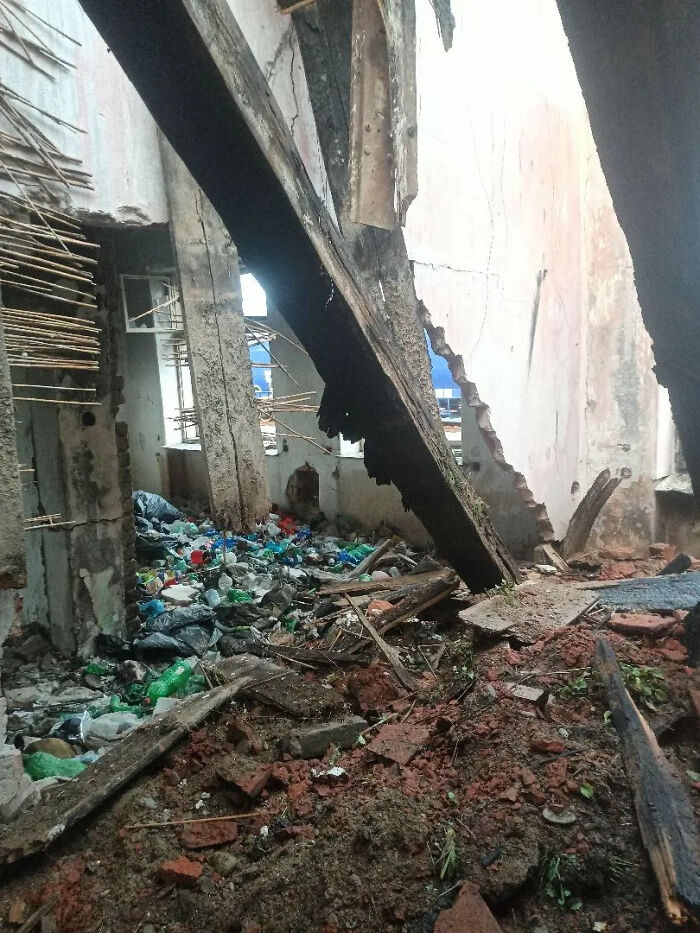 Urban exploration of a crumbling building interior filled with rubble, trash, and broken wooden beams.