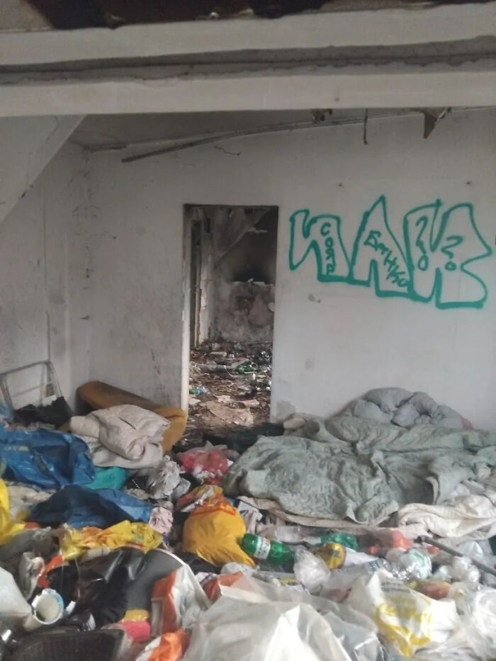 A room filled with trash and graffiti on the wall, depicting the decay often found during urban exploration.