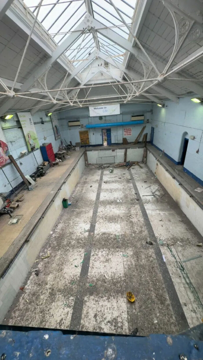 A derelict indoor swimming pool with a collapsed ceiling, captured during urban exploration at a specific location.
