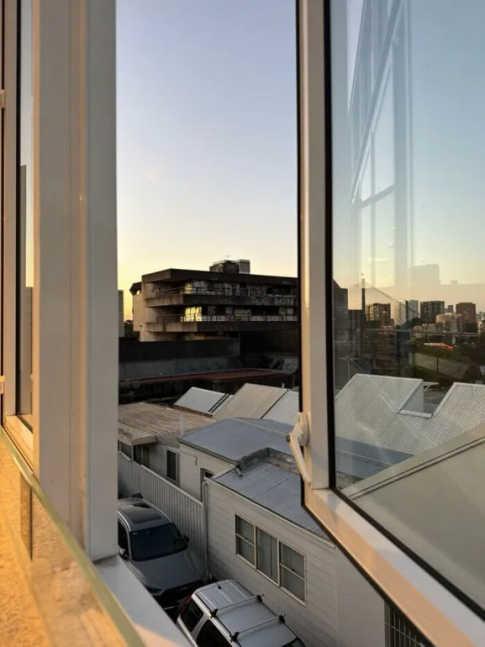 A cityscape view from an open window at sunset, showing urban exploration from a height.
